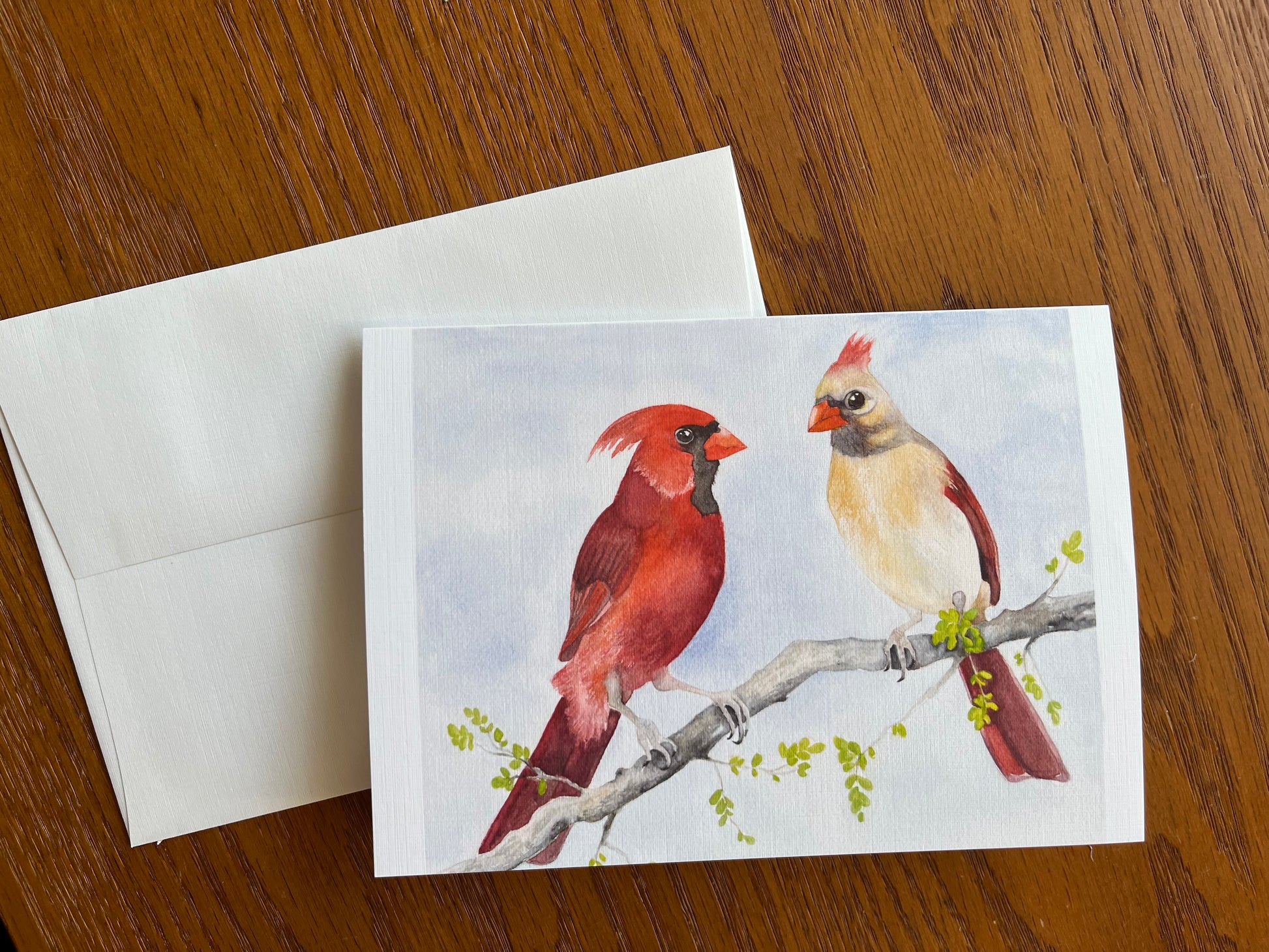 Greeting card and envelope with a watercolor painting of a male and female cardinal sitting on a branch.