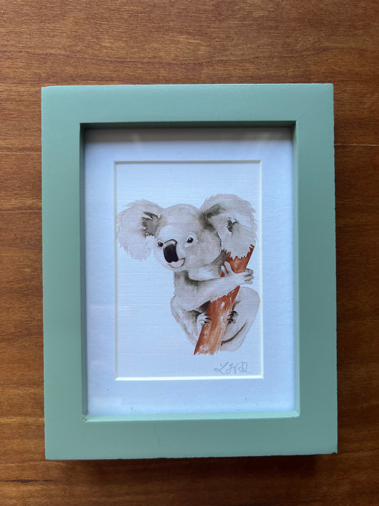 Koala watercolor painting in a small green frame.