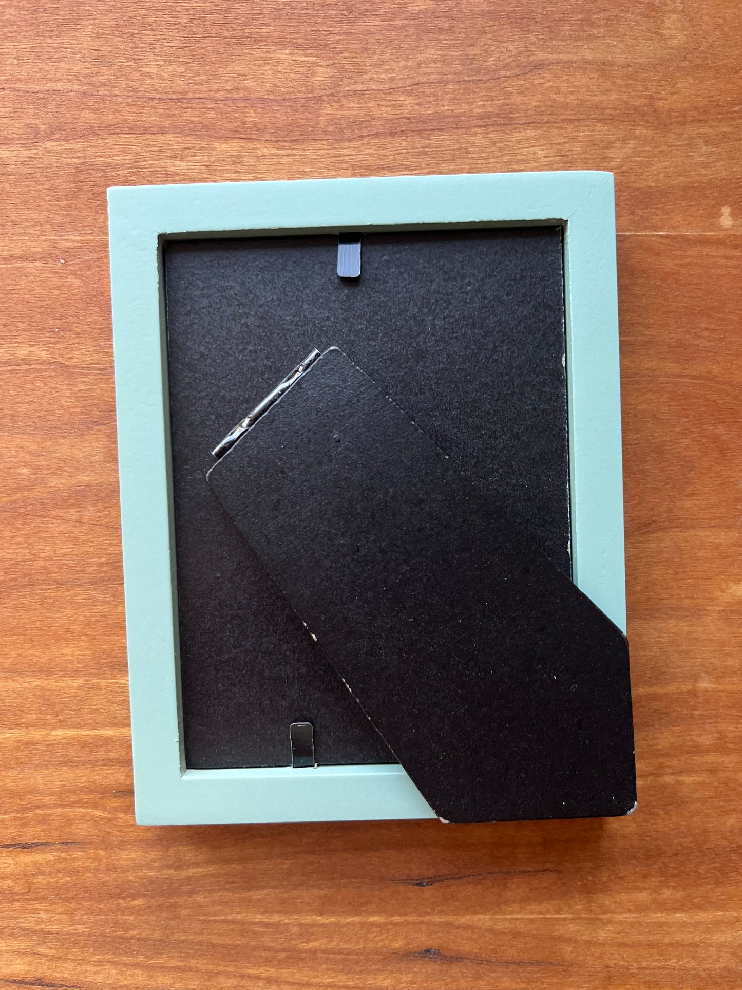 The back of a small green picture frame.
