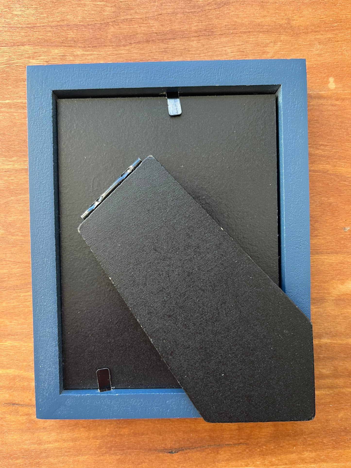 The back of a small blue picture frame.