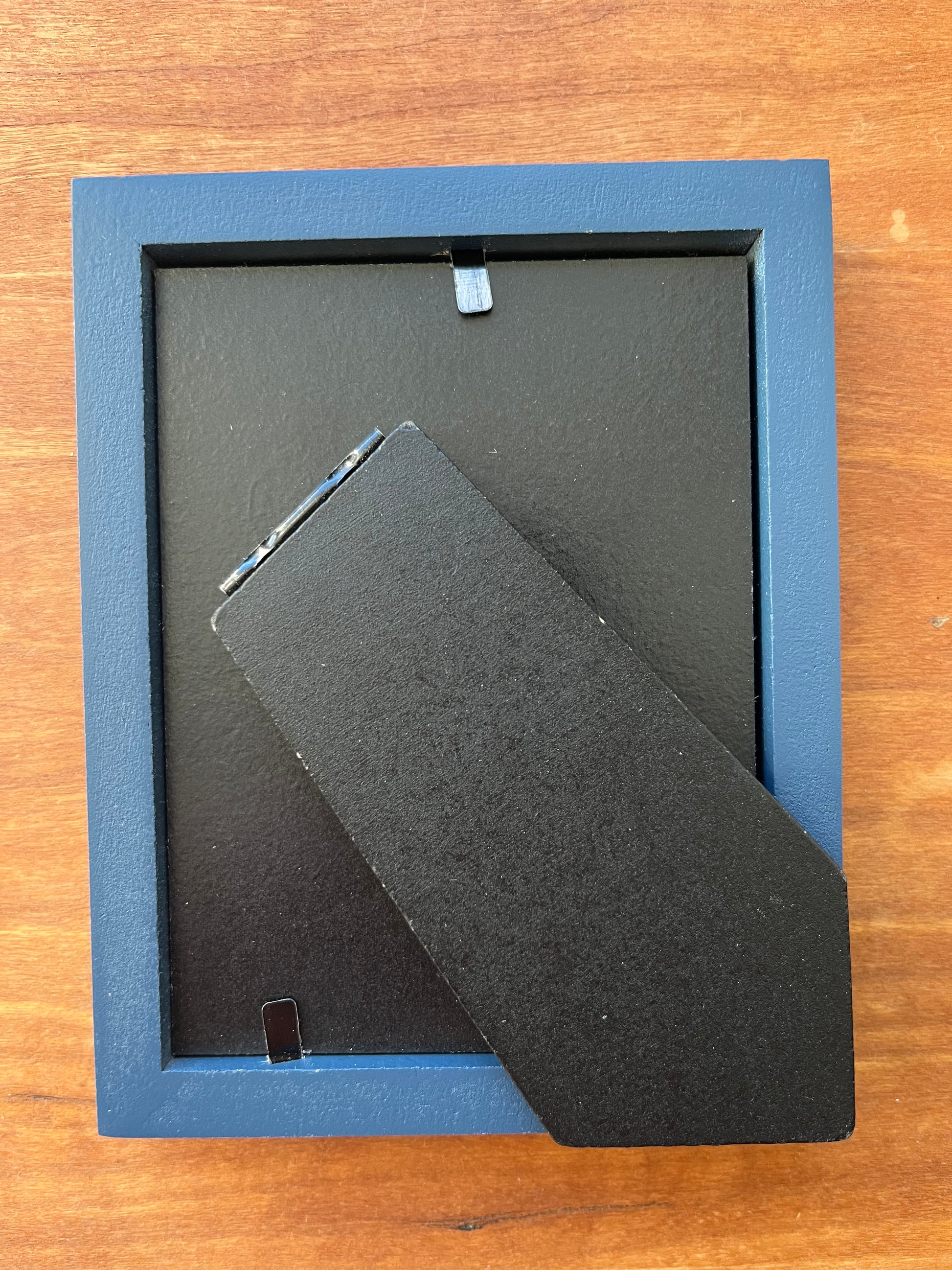 The back of a small blue picture frame.