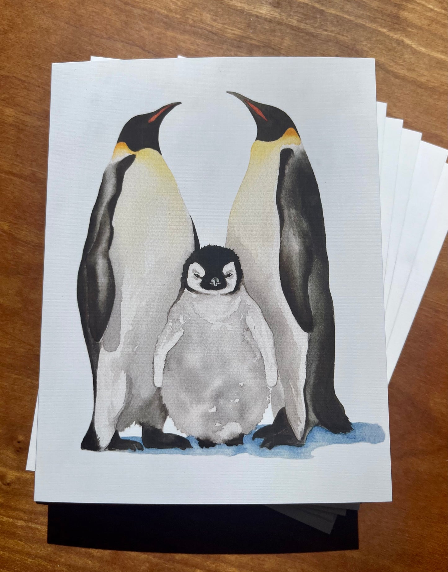 Watercolor painting of an emperor penguin family on six greeting cards.