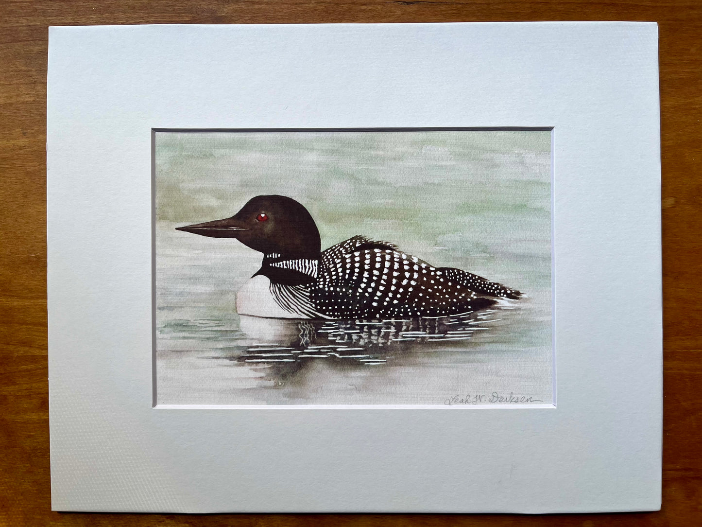 Watercolor painting of a loon in a white matte.