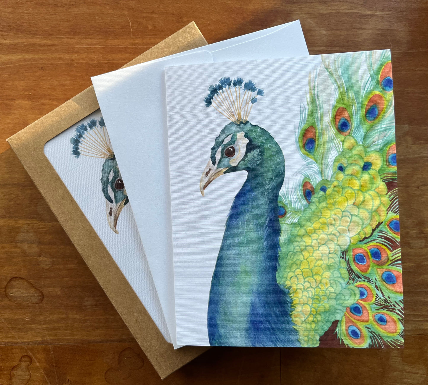 Watercolor peacock greeting card with a white envelope.