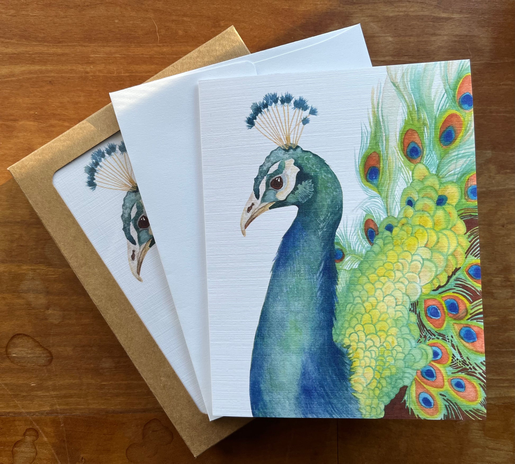 Watercolor peacock greeting card with a white envelope.