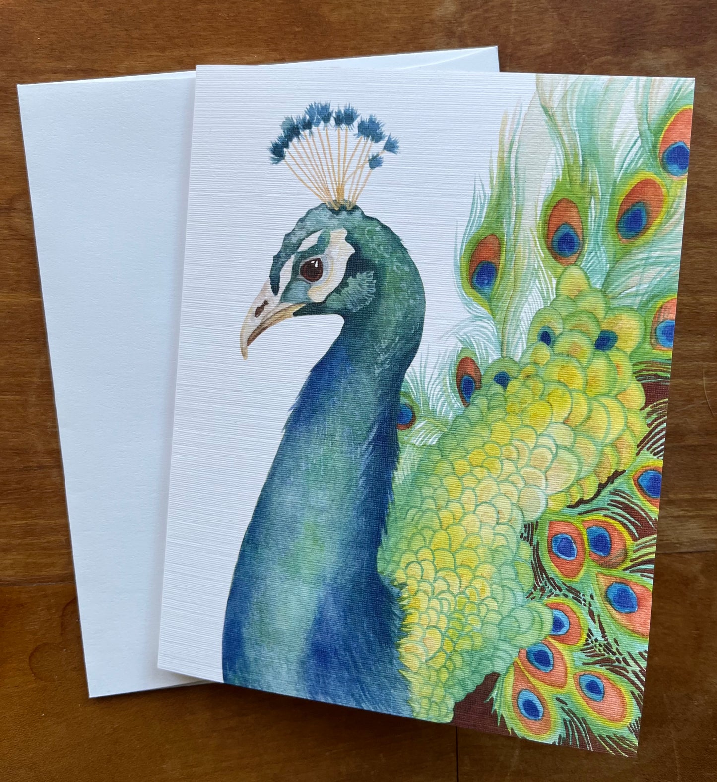 Watercolor peacock greeting card with a white envelope.