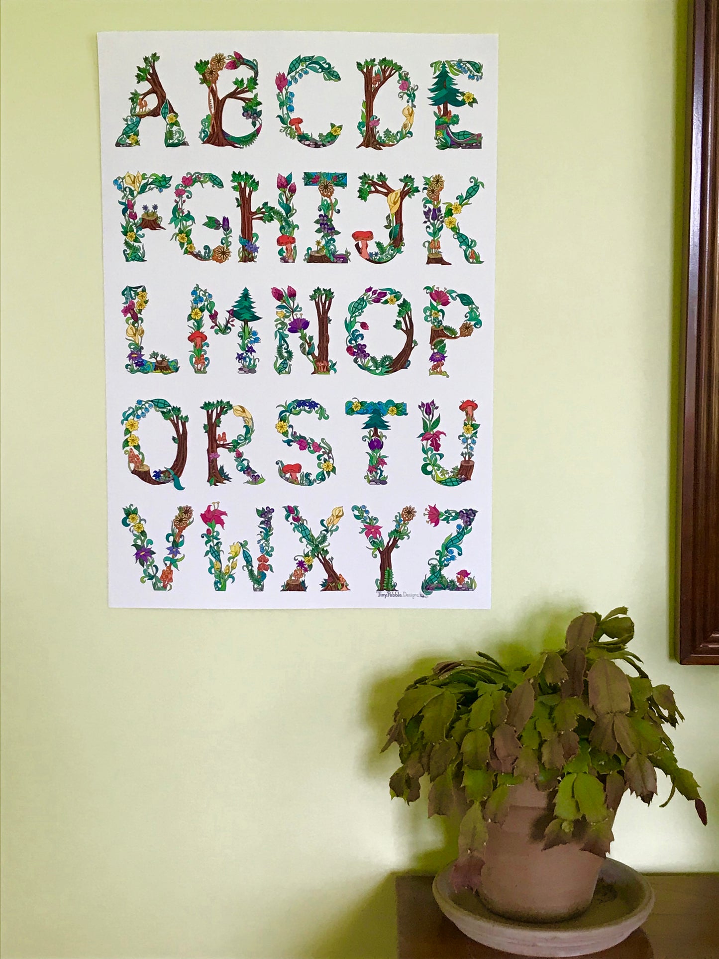 13x19 botanical alphabet poster hung on a wall.