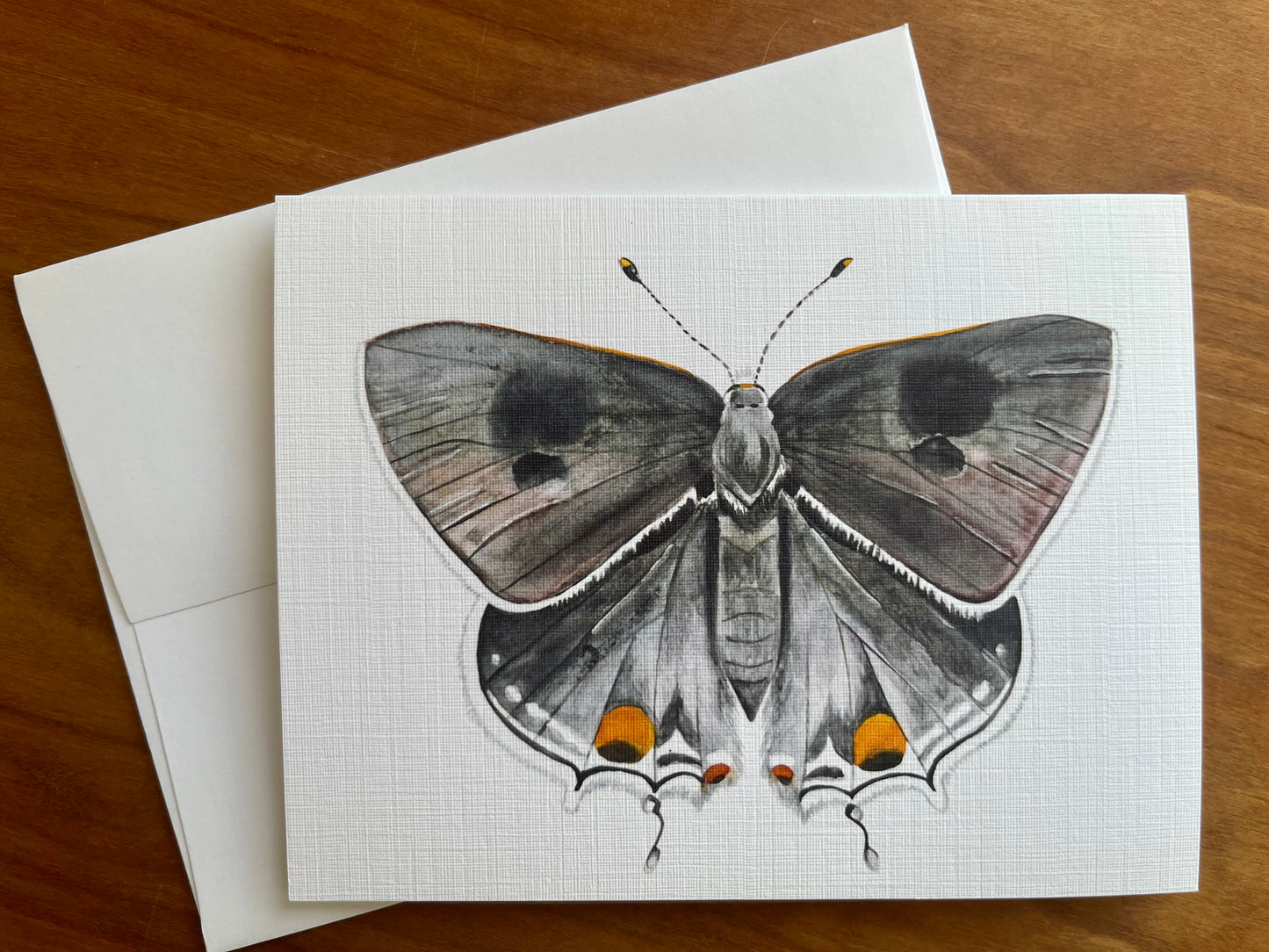 Greeting card with a watercolor painting of a grey butterfly along with a white envelope.