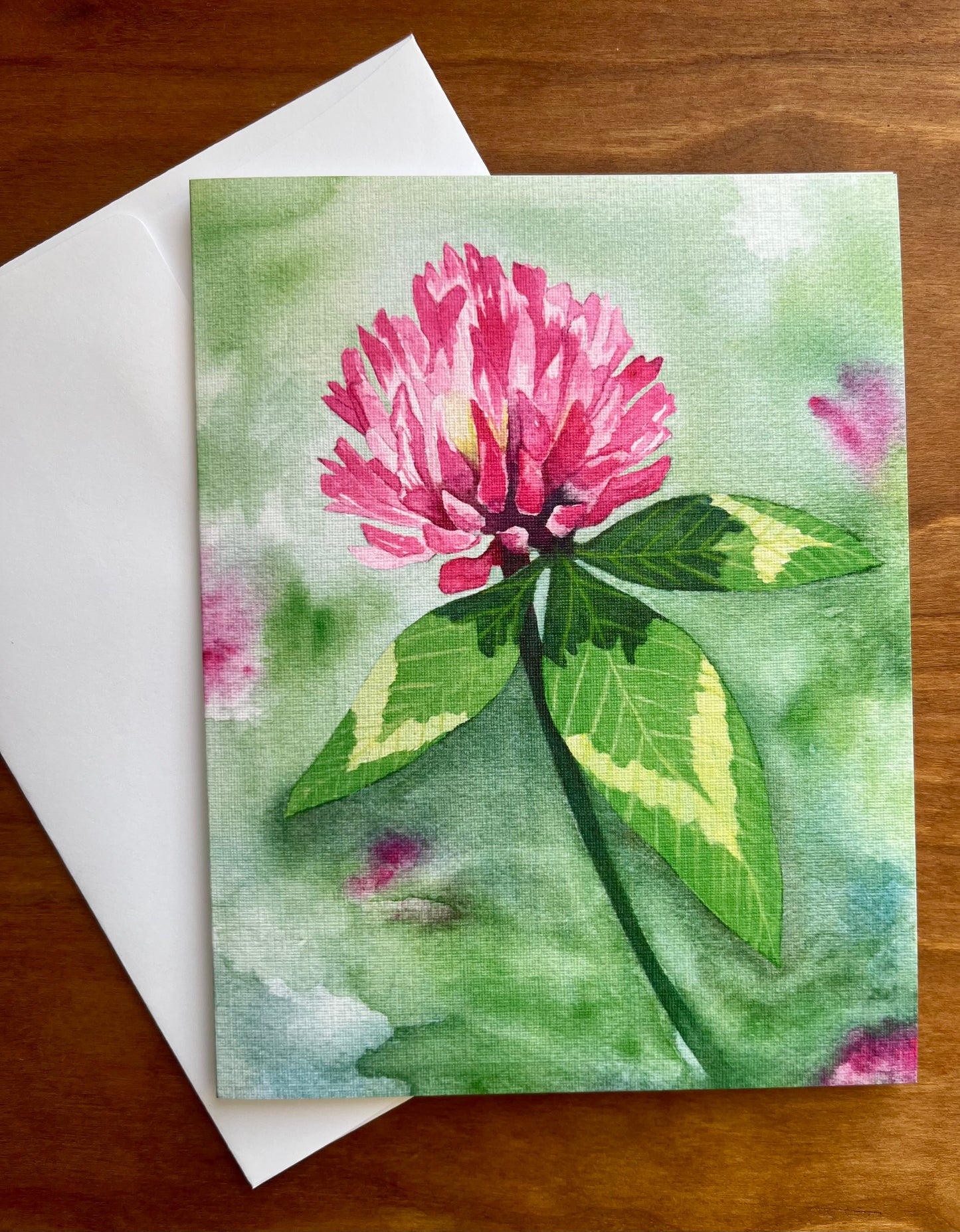 Greeting card with a watercolor painting of a red clover flower along with a white envelope.