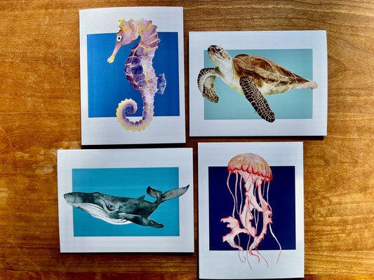 four greeting cards with one of each watercolor painting of a sea turtle, seahorse, whale, and jellyfish.