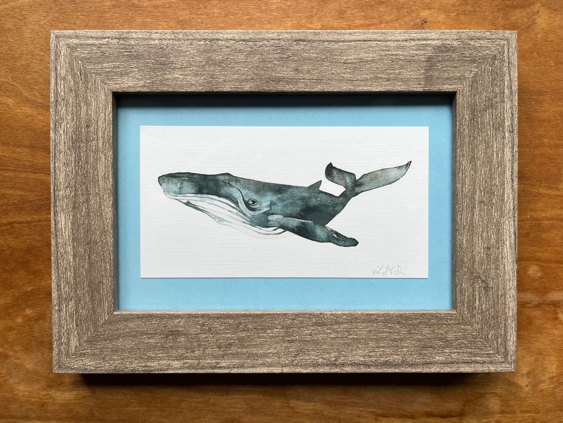 Watercolor whale in a grey wood frame with a light blue matte.