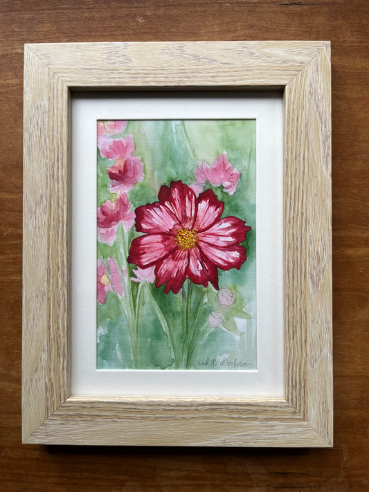 Watercolor painting of pink cosmos flowers in a blonde wood picture frame.