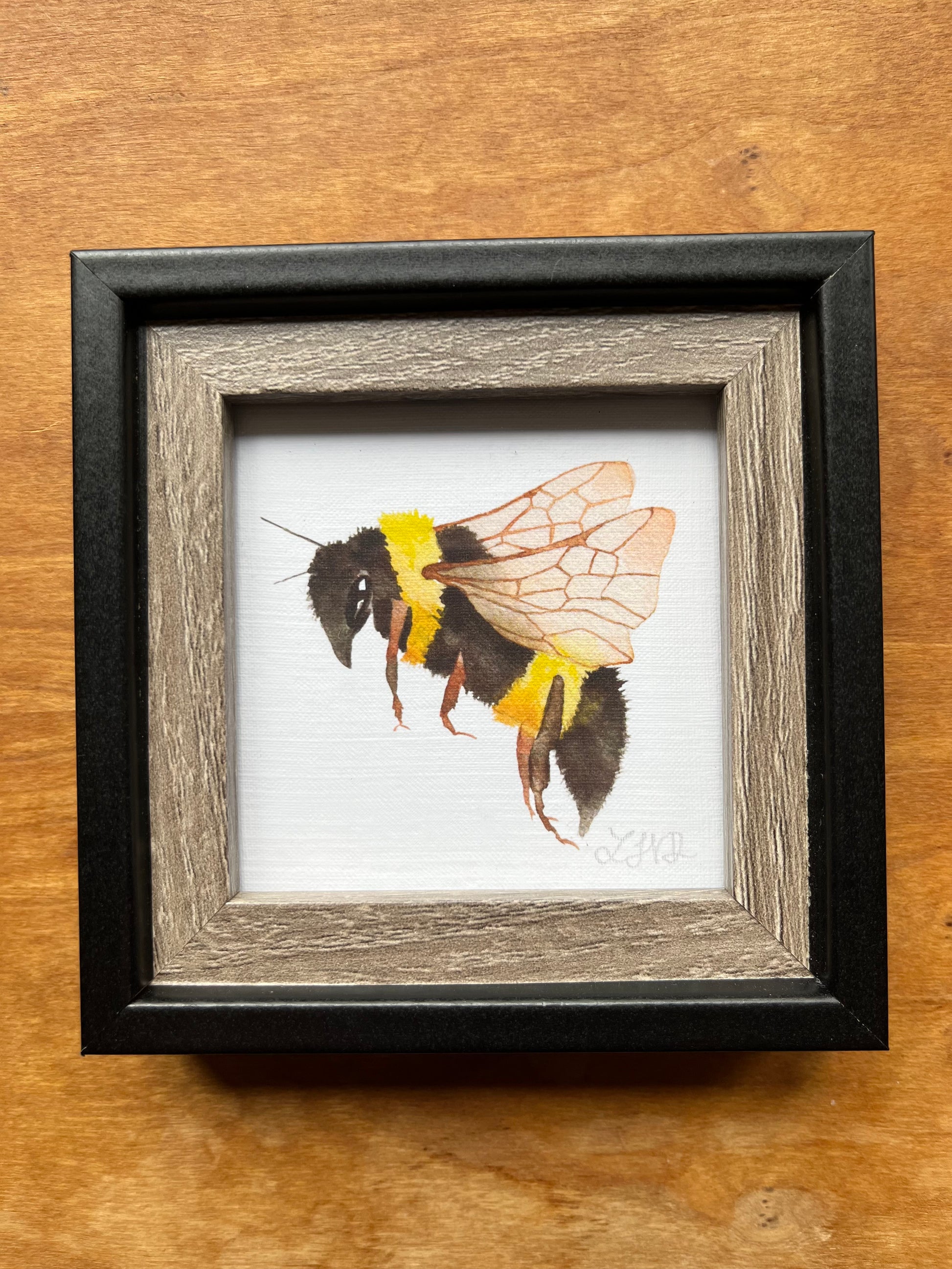 Black and wood square picture frame with a watercolor bee.