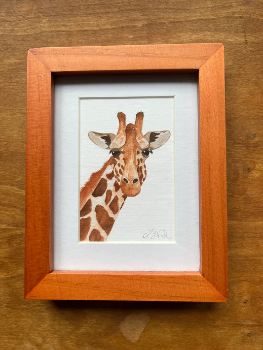 Watercolor giraffe in a honey colored wood picture frame.