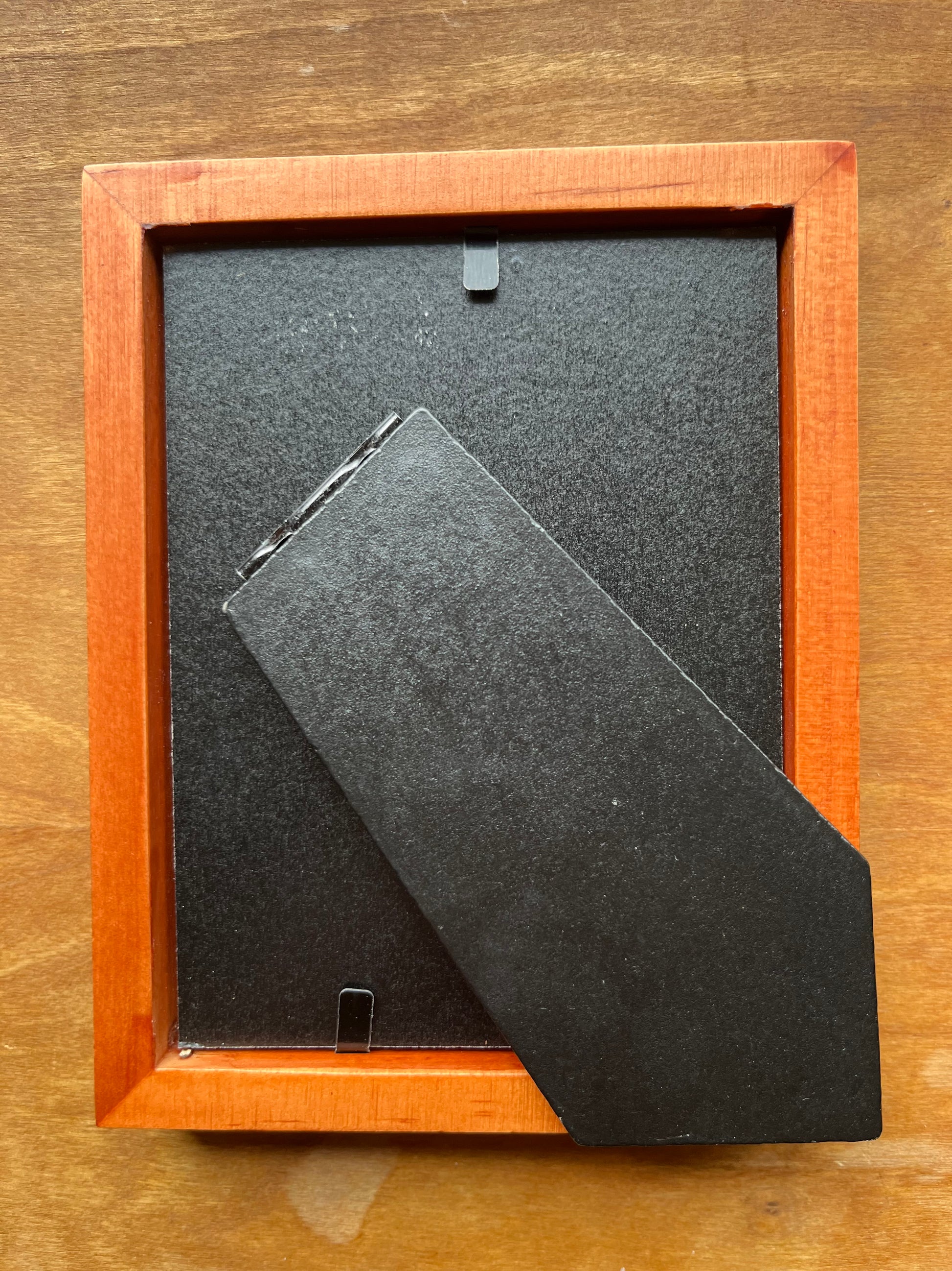 Back of honey colored wood picture frame.