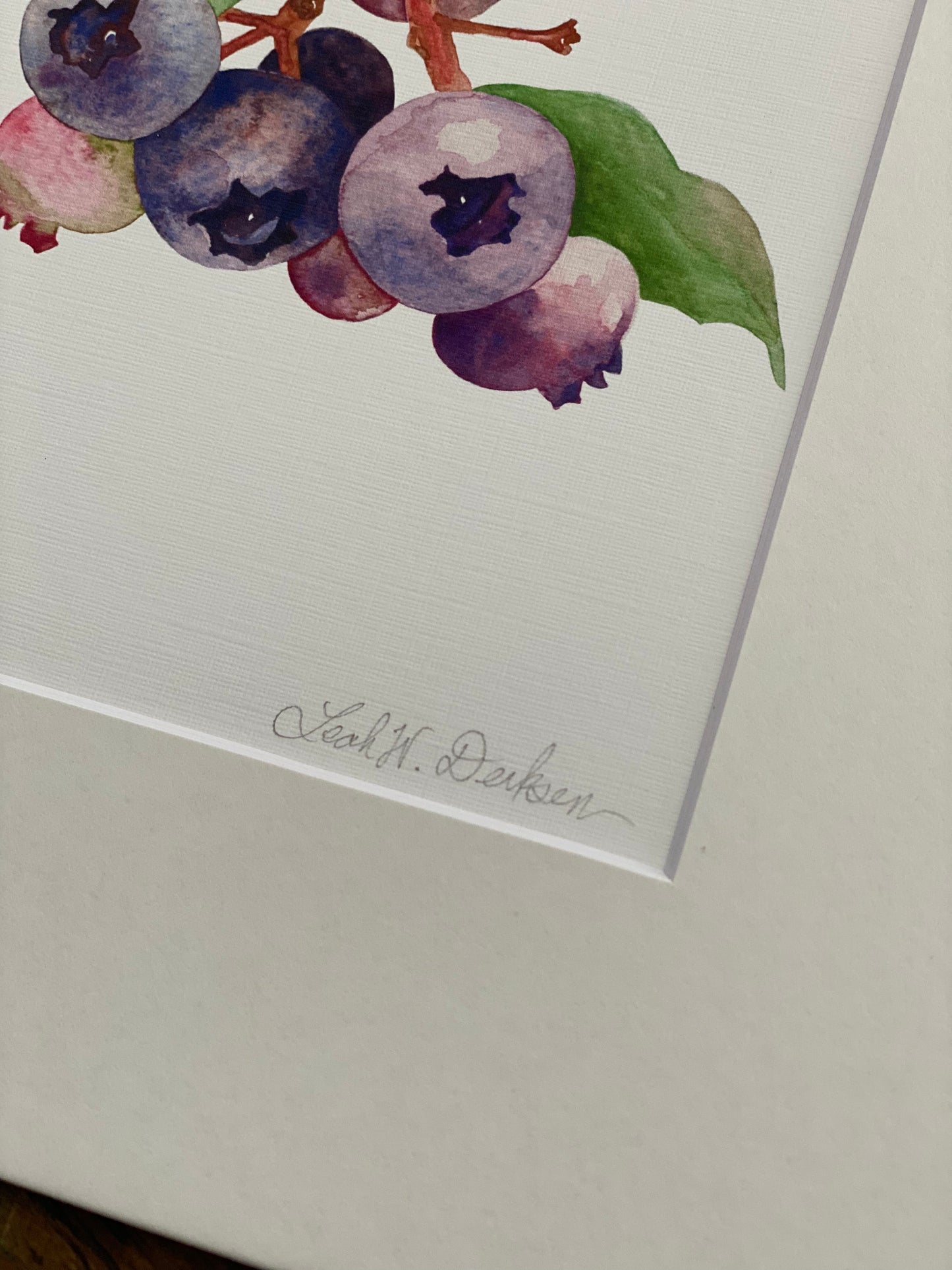 matted print of watercolor blueberries close up to show artist signature.