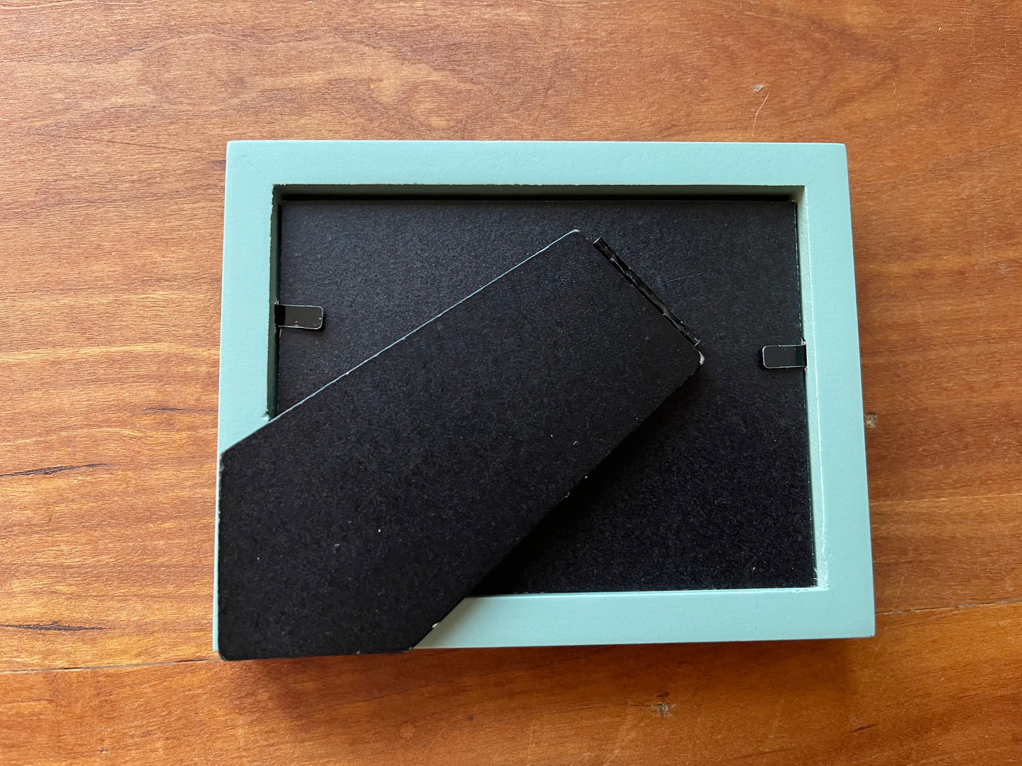 The back of a small green picture frame. 