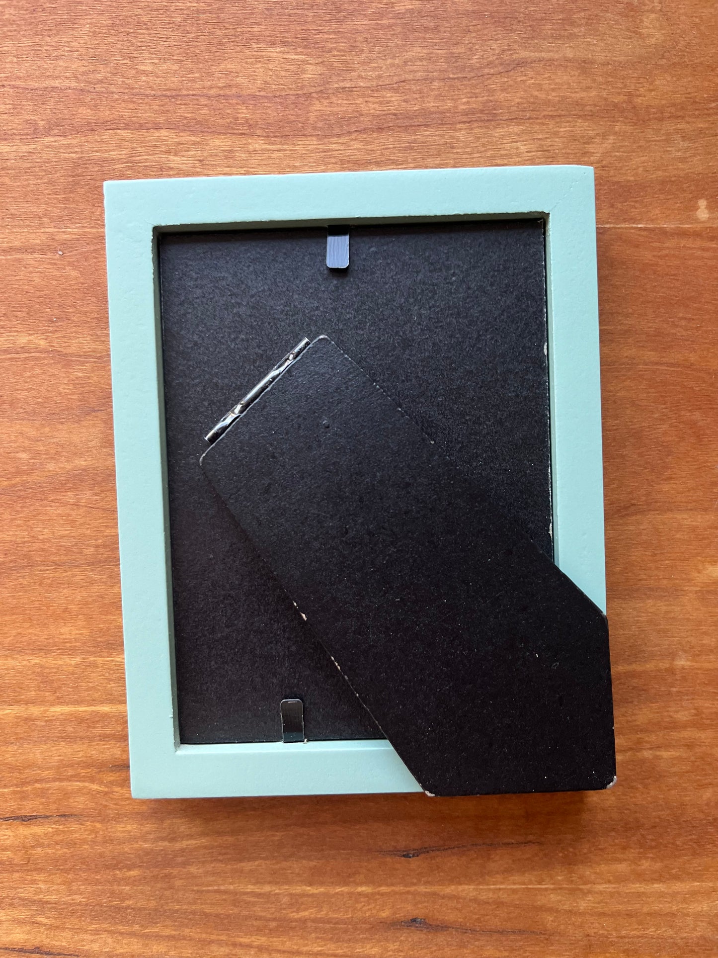 The back of a small green picture frame. 