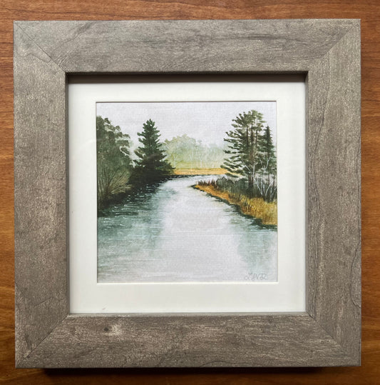 Watercolor painting of a river with trees in a grey picture frame with a white matte