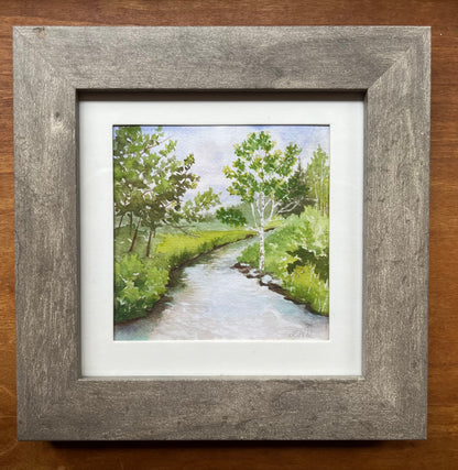 Watercolor of a green forest with a river framed in grey with a white matte