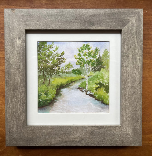 Watercolor of a green forest with a river framed in grey with a white matte