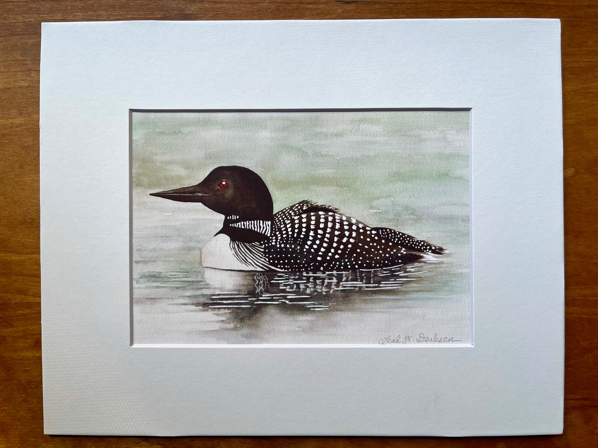 Watercolor painting of a loon in a white matte. 