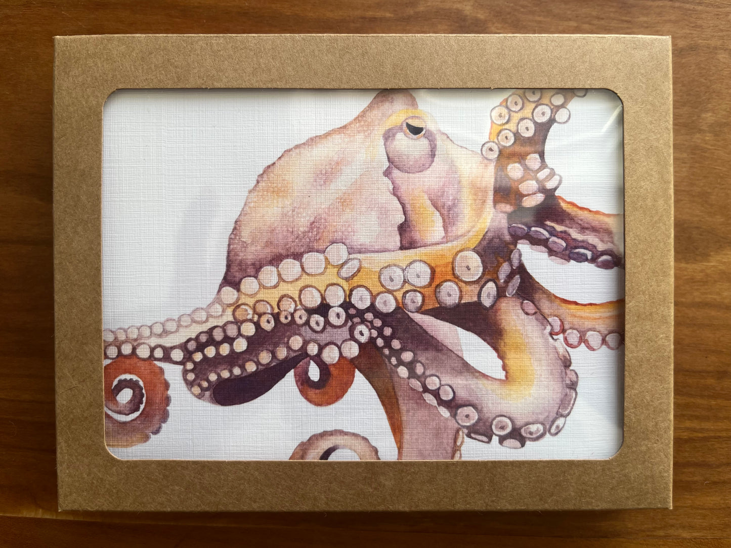 A brown Kraft box containing greeting cards with a watercolor painted octopus on them. 