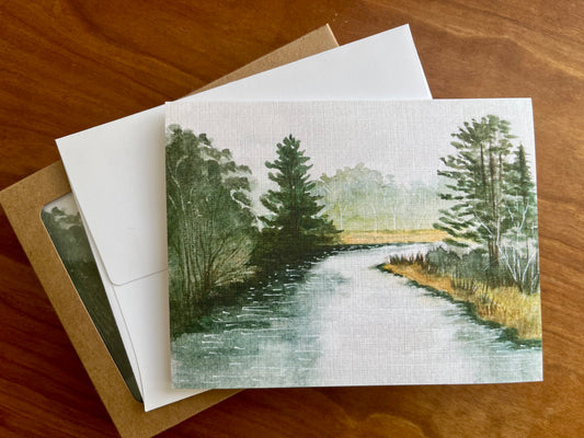 Greeting card with a painting of a Vermont river and forest along with a white envelope. 