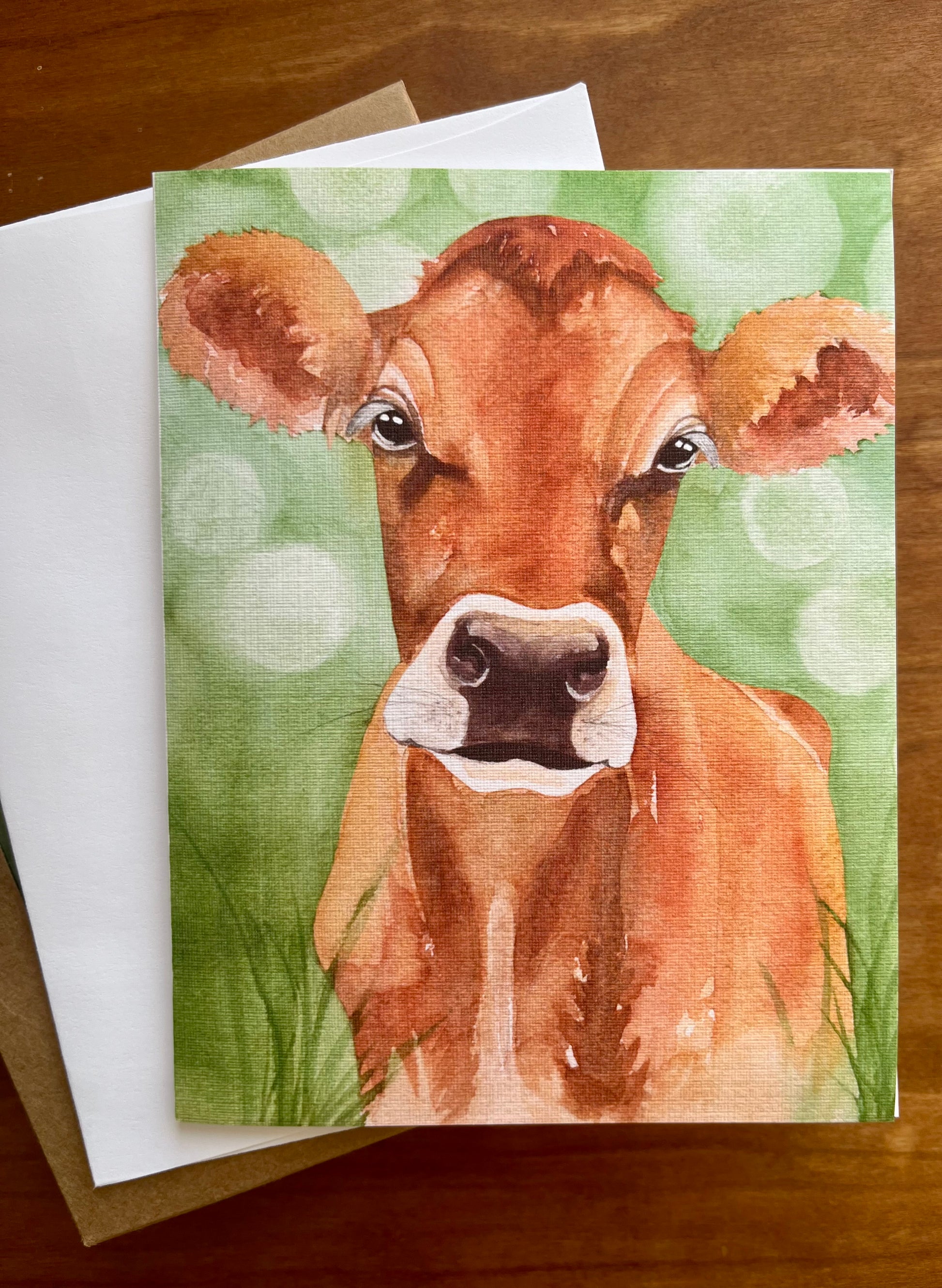 Greeting card with a watercolor painting of a jersey cow in a green field. 