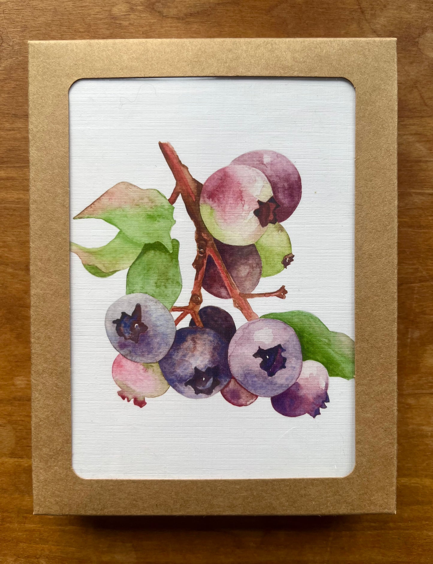 Kraft box containing a set of greeting cards with a watercolor painting of blueberries. 