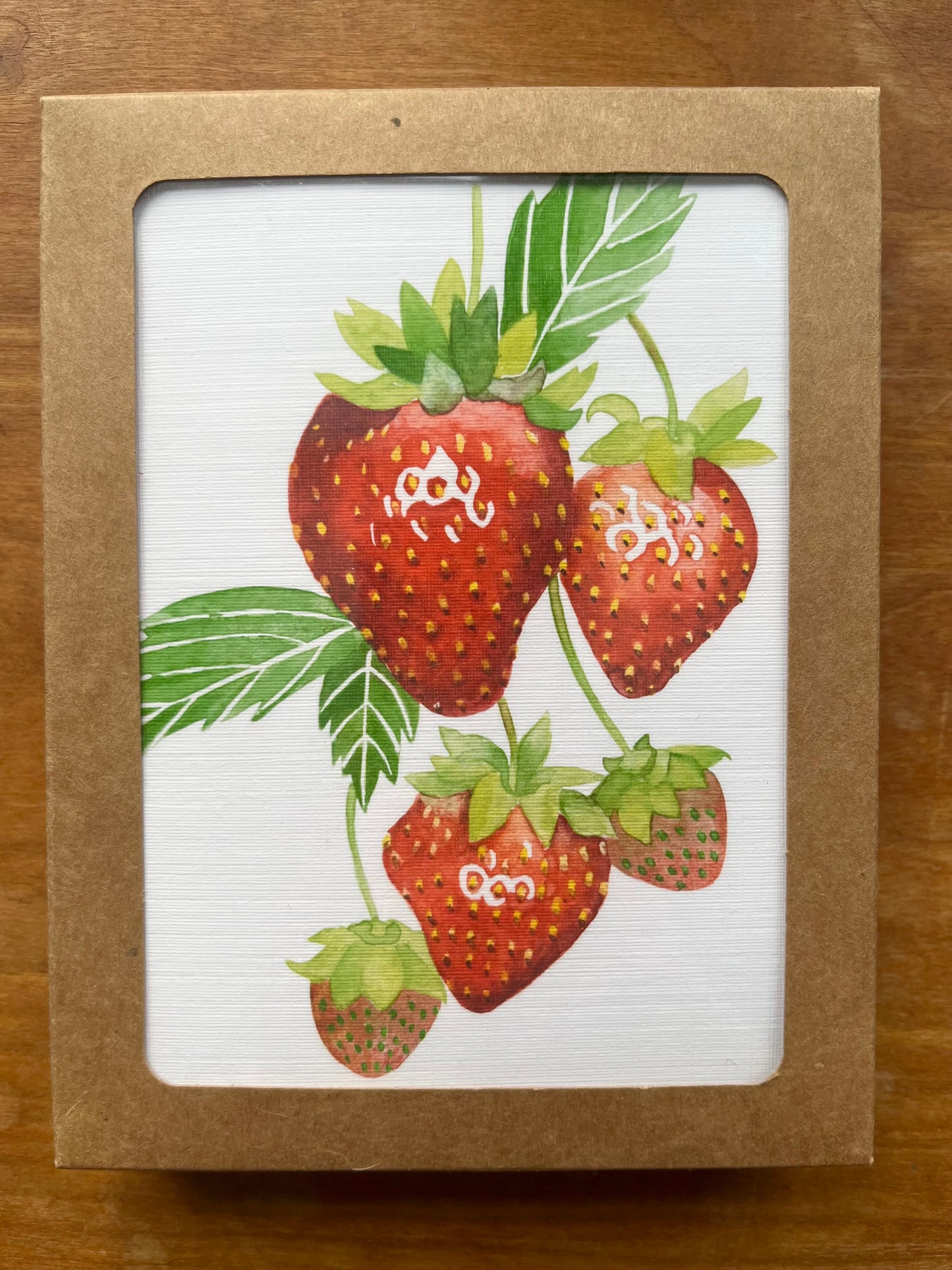 Kraft box containing greeting cards with a watercolor painting of strawberries. 