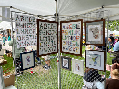 Botanical alphabet posters hung for display at an artisan fair. 