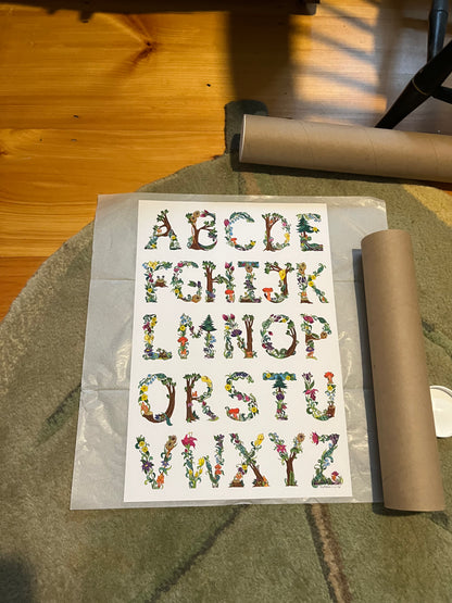 botanical alphabet poster shown with shipping materials including a mailing tube and tissue paper. 