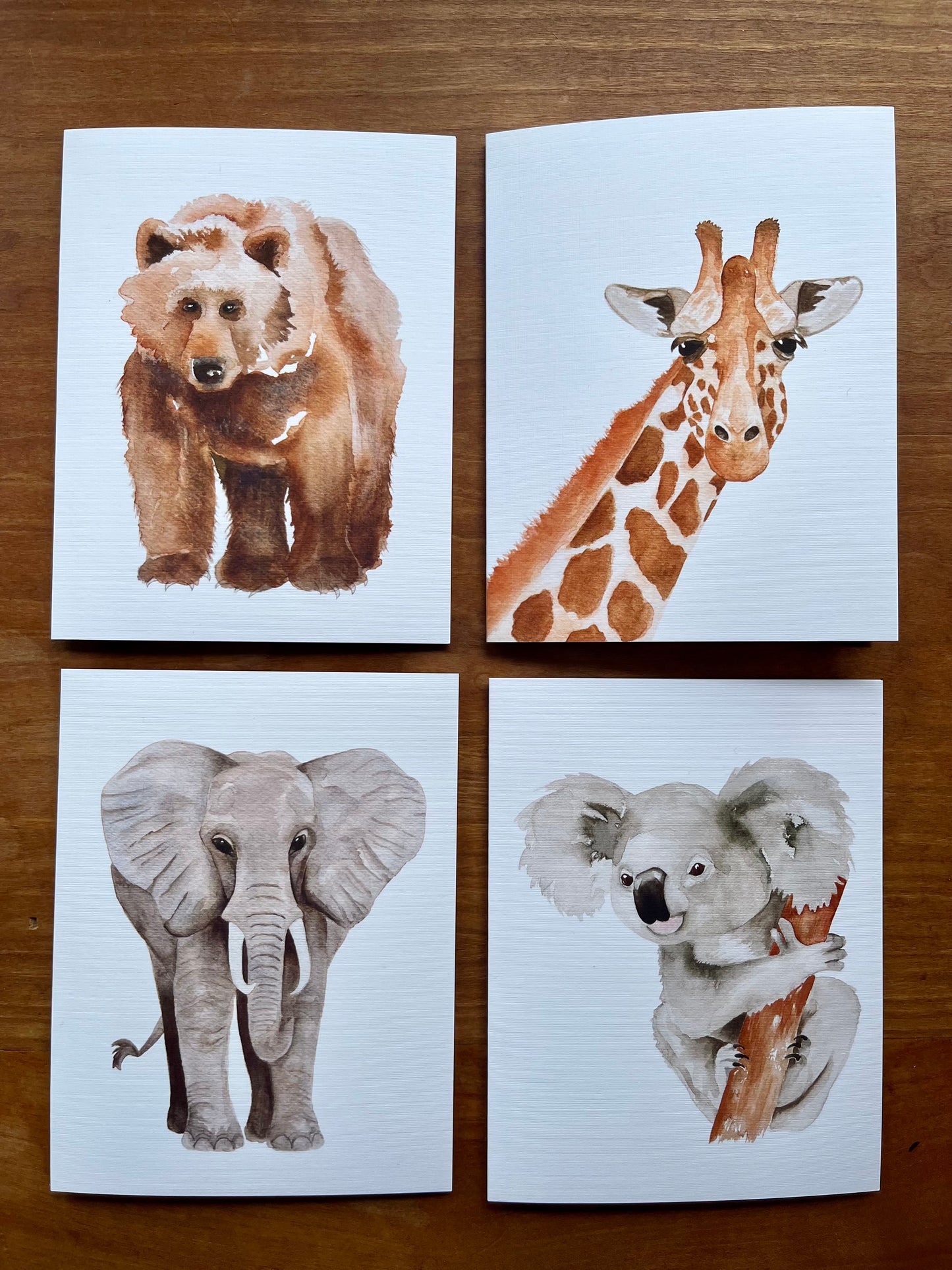 a set of four greeting cards one each of a watercolor bear, giraffe, elephant, and koala.