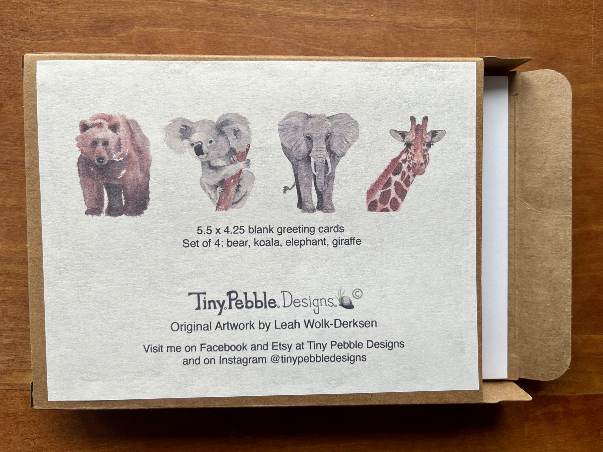 a greeting card box displaying the contents of four watercolored cards including one of each bear, koala, elephant, and giraffe. 