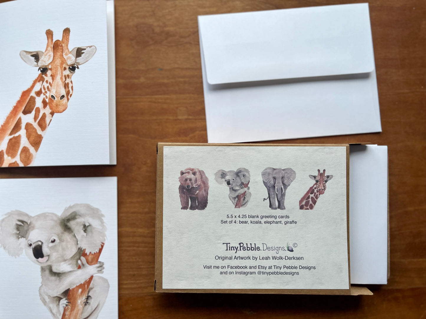 a display of greeting cards with a watercolor giraffe and koala.