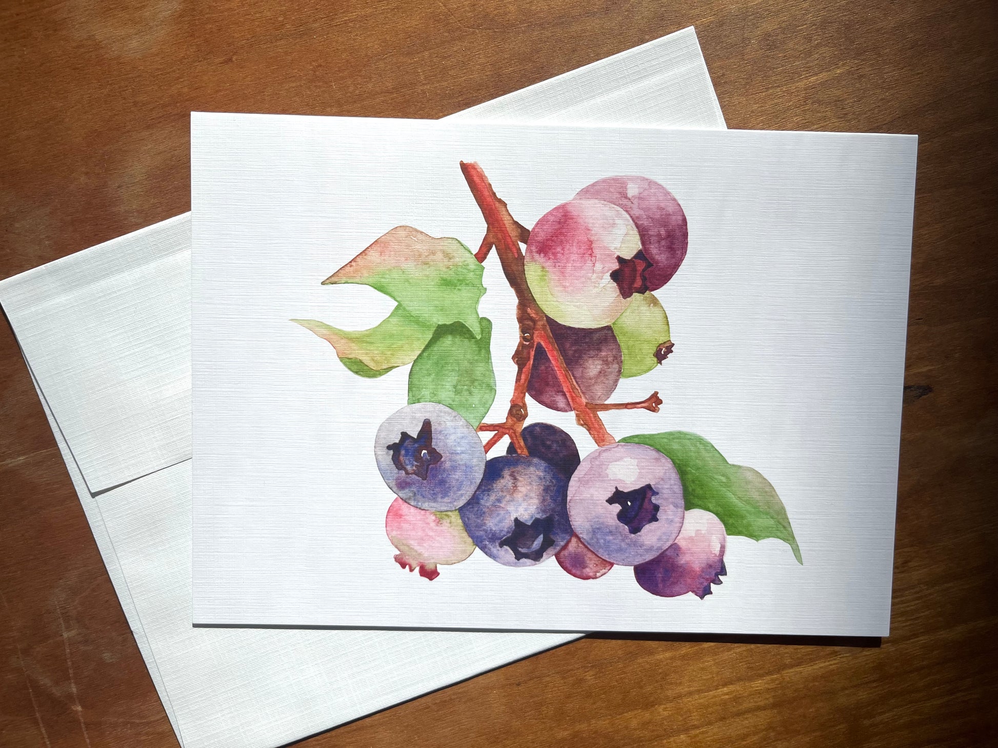 watercolor blueberries printed on a greeting card and shown with an envelope. 