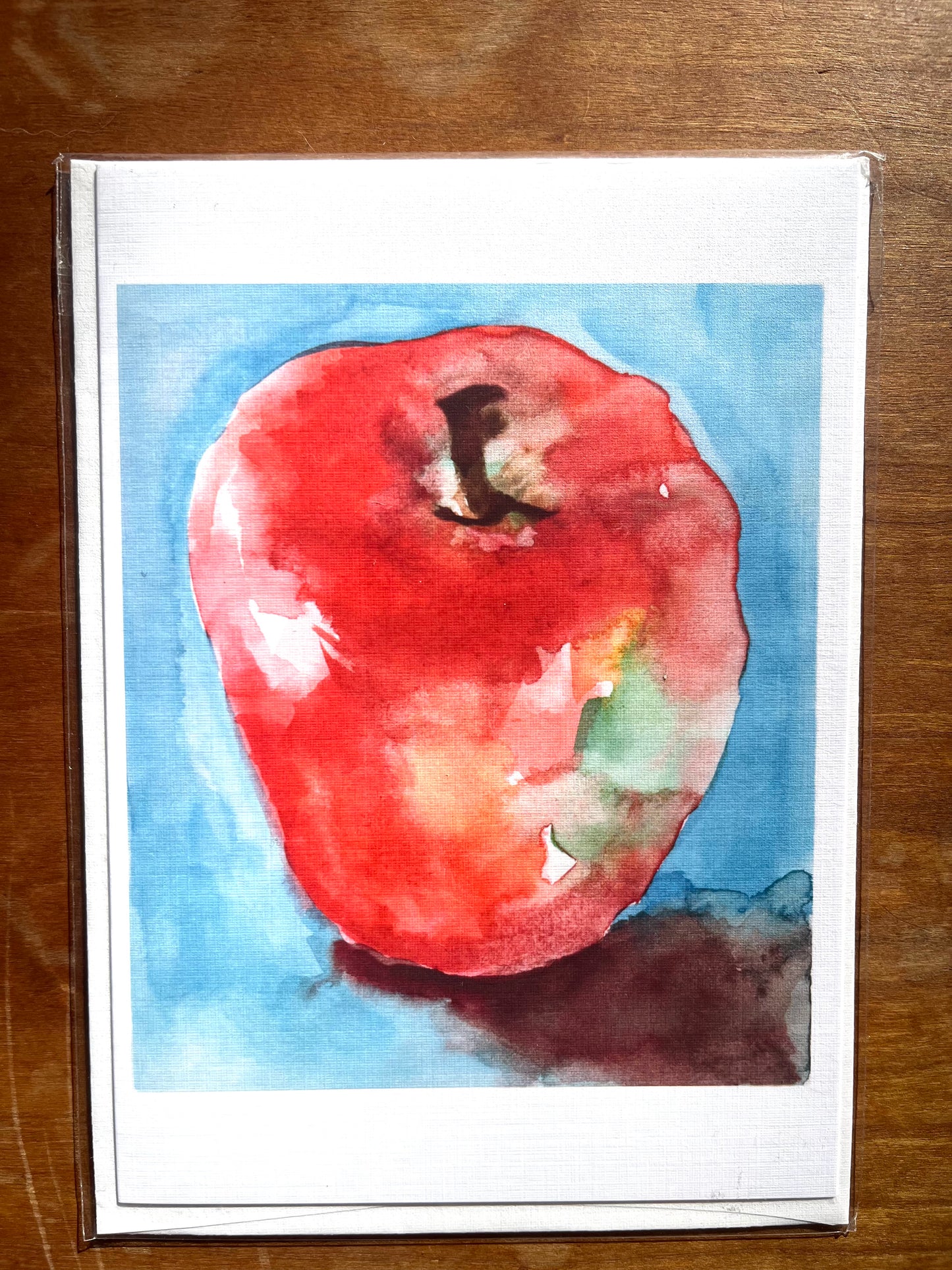 Watercolor painting of a red apple printed on a greeting card.