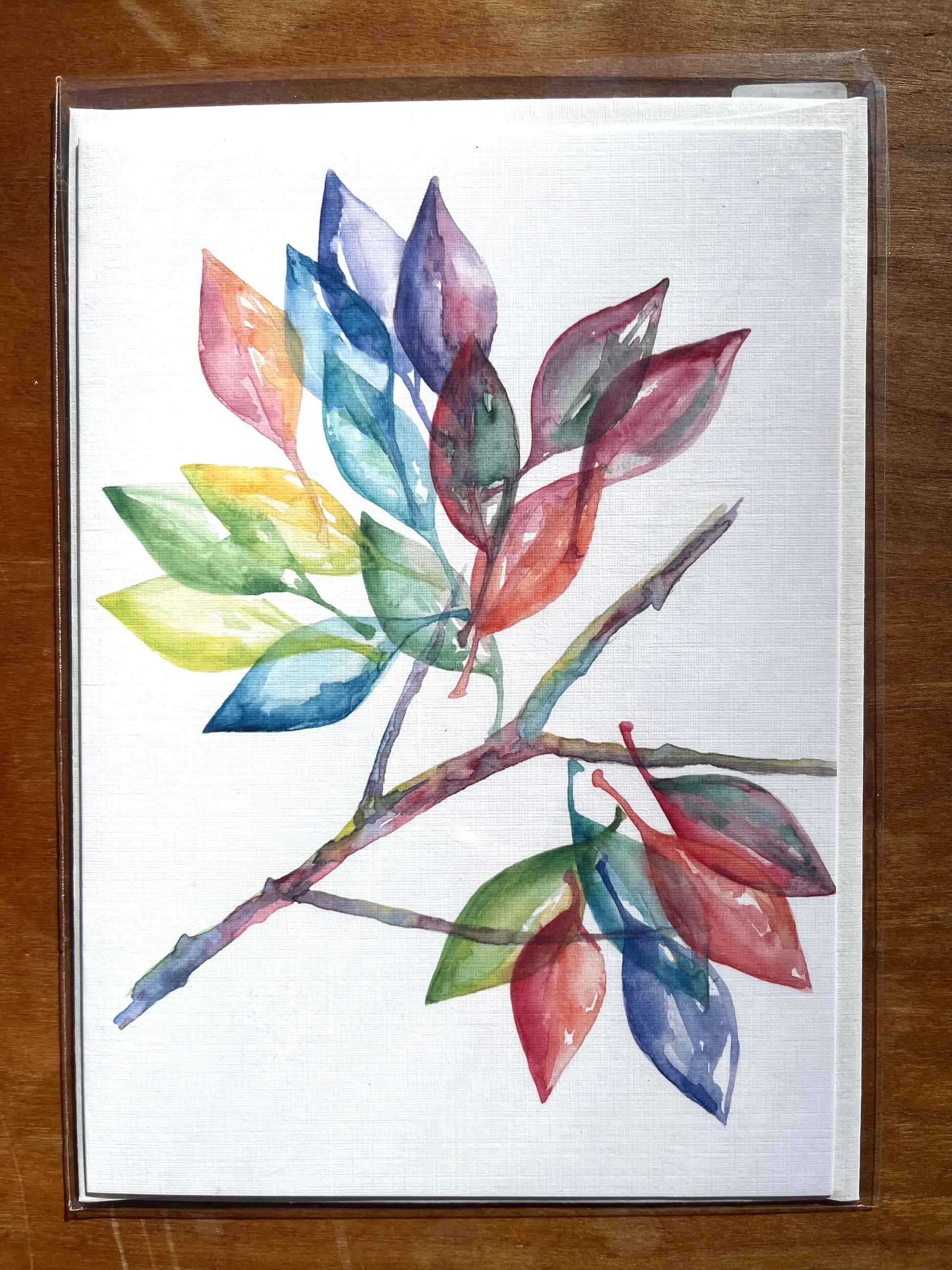 5x7 greeting card with a watercolor painting of multi-colored leaves on a branch. 