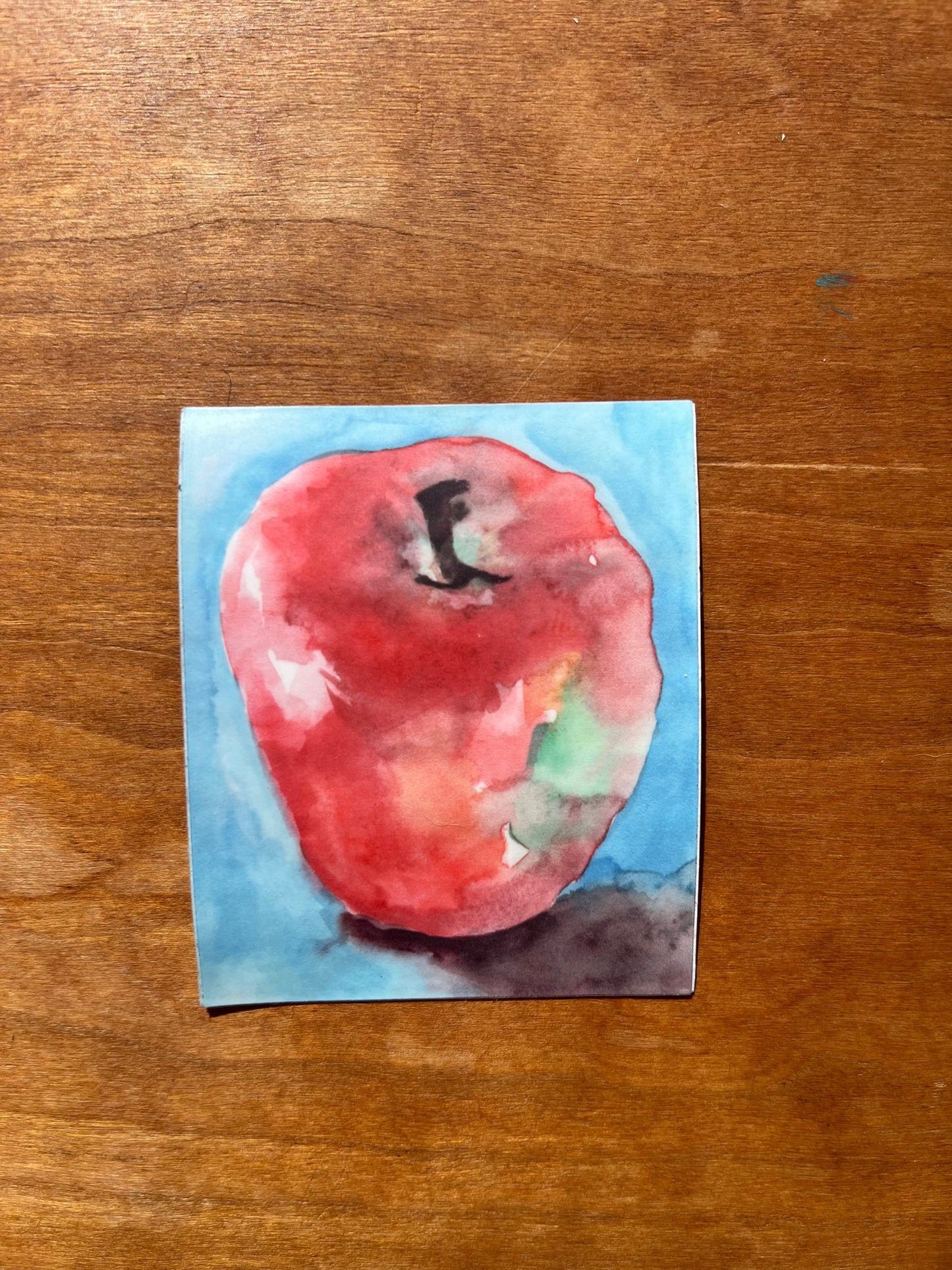 a rectangular sticker with a watercolor painting of a red apple.