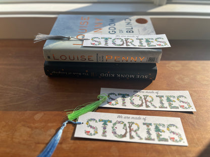 a collection of bookmarks that say, we are made of stories, displayed with a stack of books.