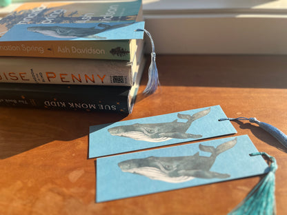 a collection of bookmarks with watercolor whales along with a display of books.