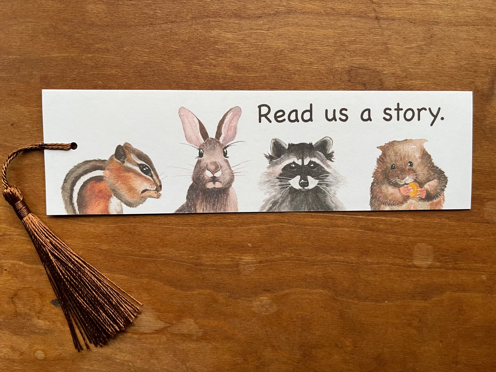 bookmark with a watercolor chipmunk, rabbit, raccoon, and vole and type that says, "read us a story".