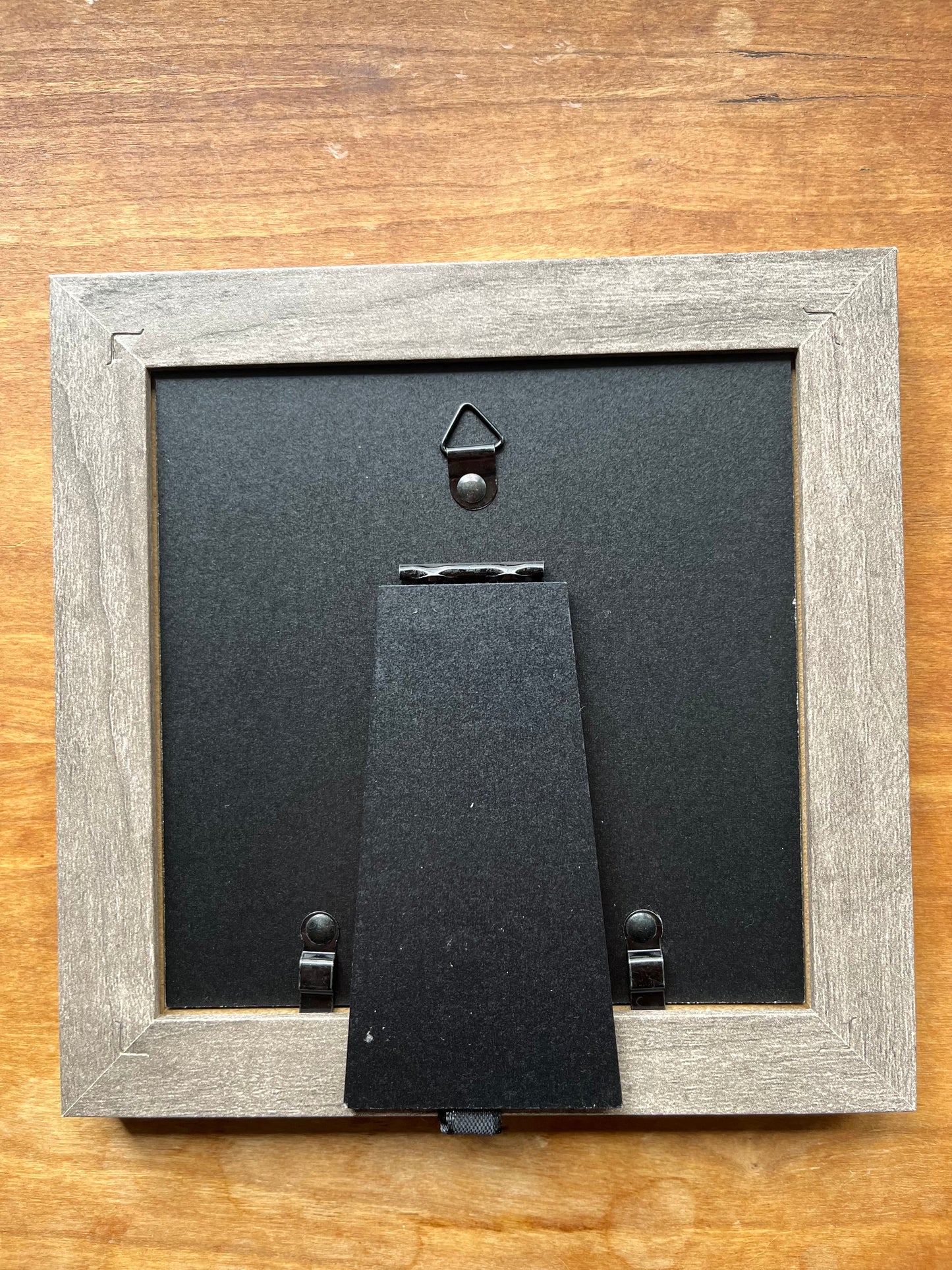 the back of a square grey picture frame.