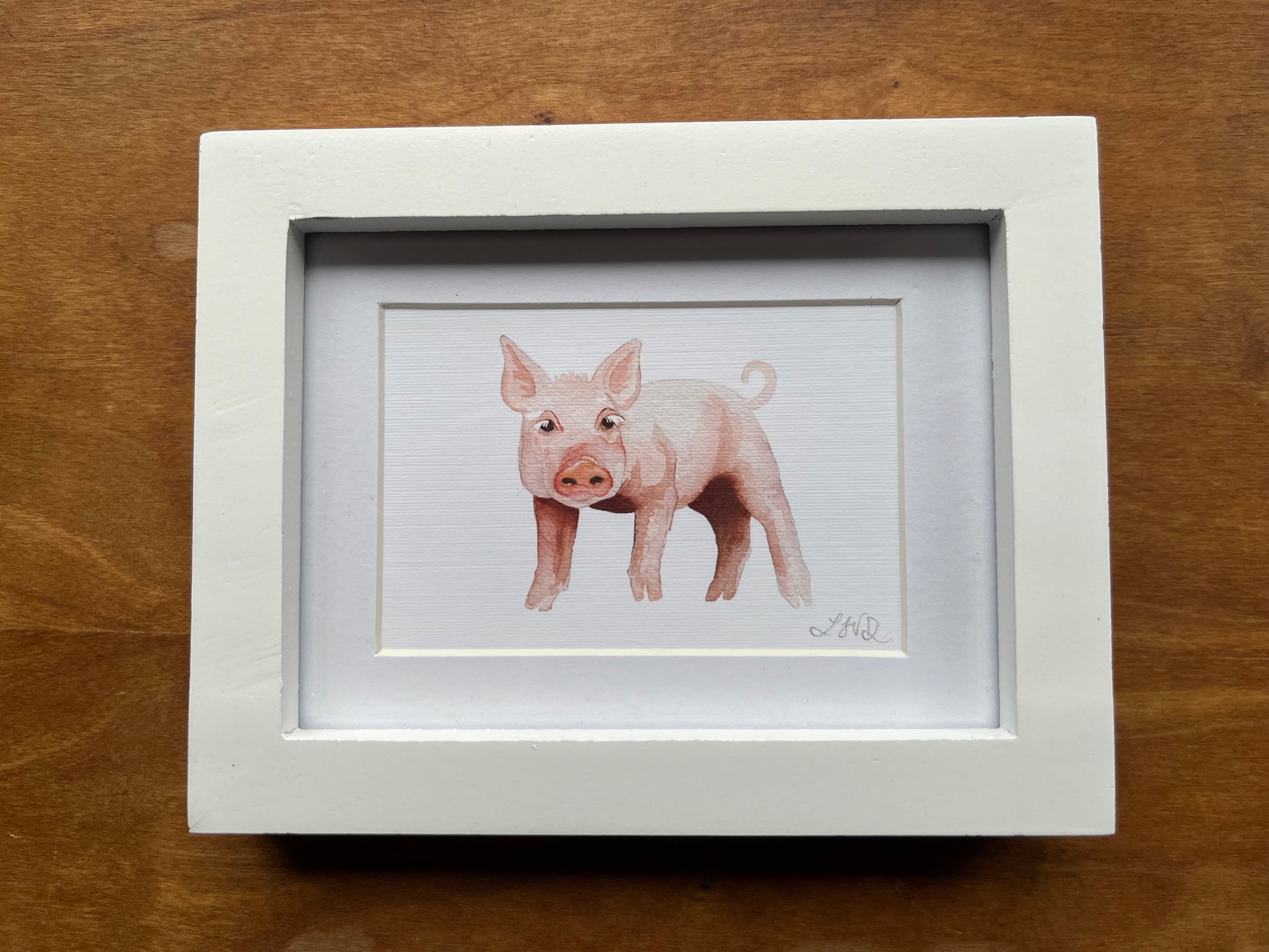 Watercolor pig in a white picture frame with a white matte. 