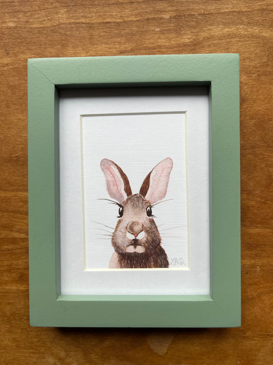 Watercolor rabbit in a green picture frame with a white matte. 