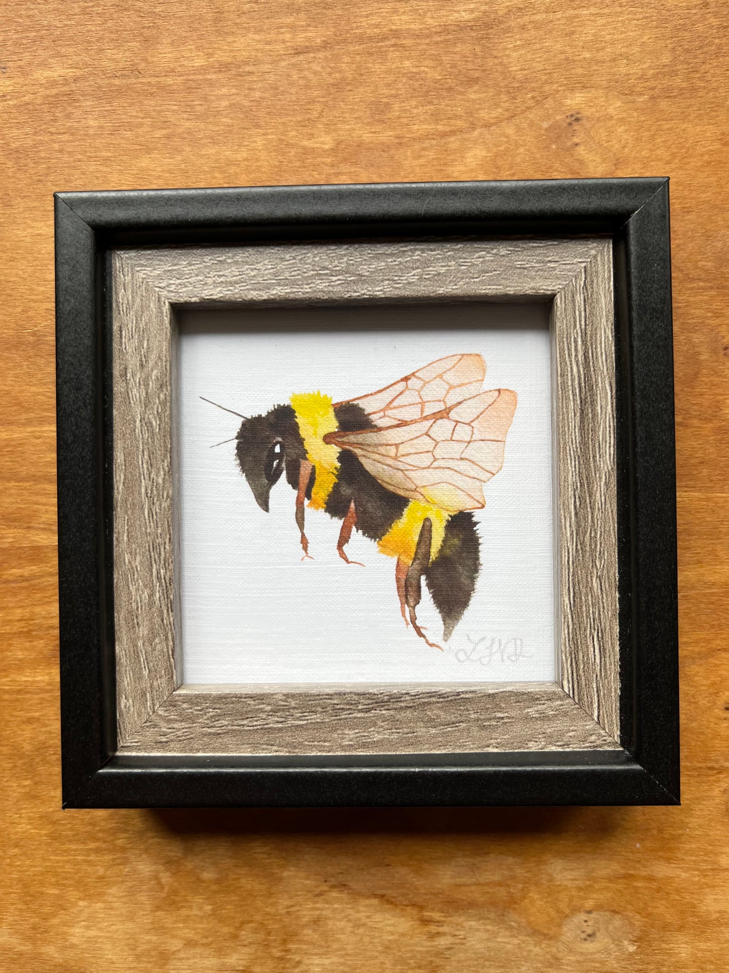 Black and wood square picture frame with a watercolor bee. 